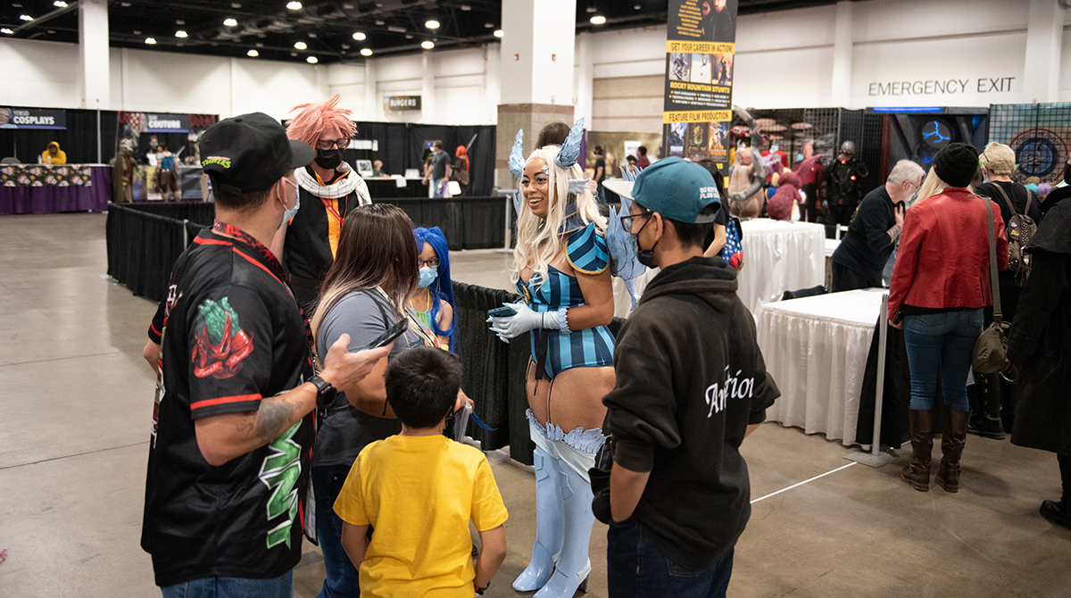 Photo of cosplayer Tif Von Batsy speaking to others. 