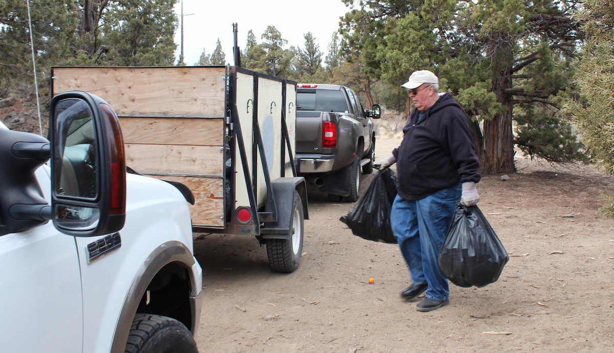 Len loads trash bags into a trailer