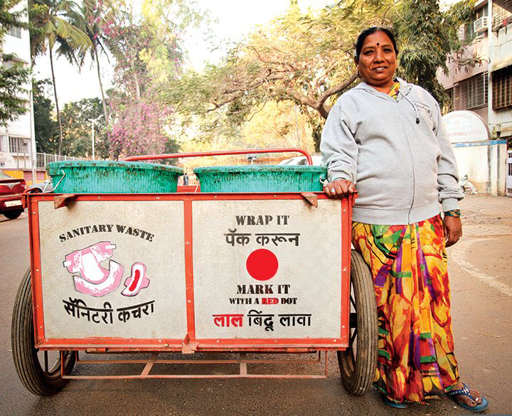A woman stands next to a waste bin for sanitary products