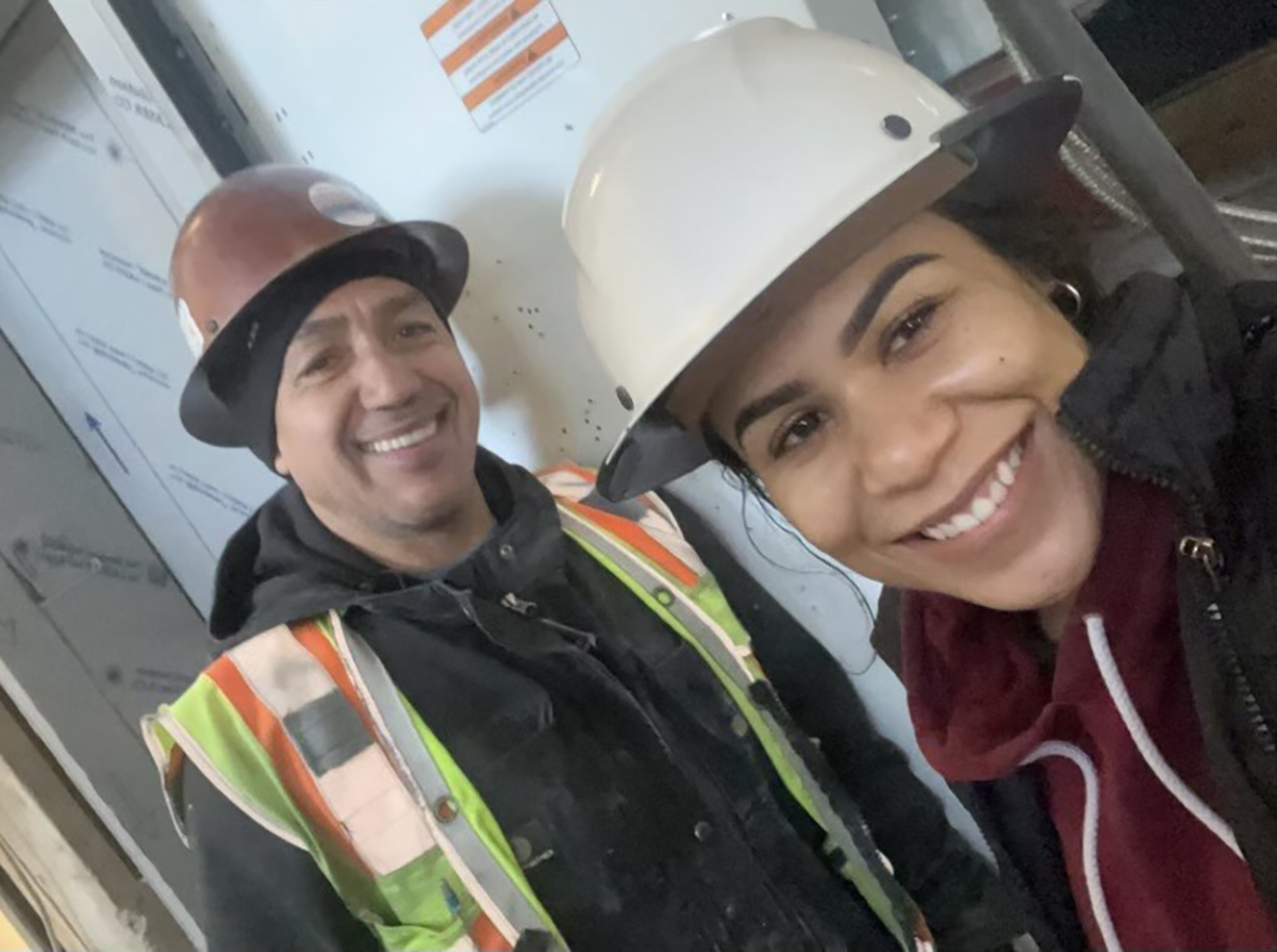 Mishele Martin and Francisco Flores smile for a photo while wearing hard hats.