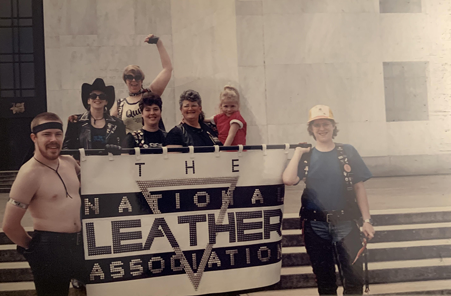 A photo of a group of people holding a sign that says "The National Leather Assocation"