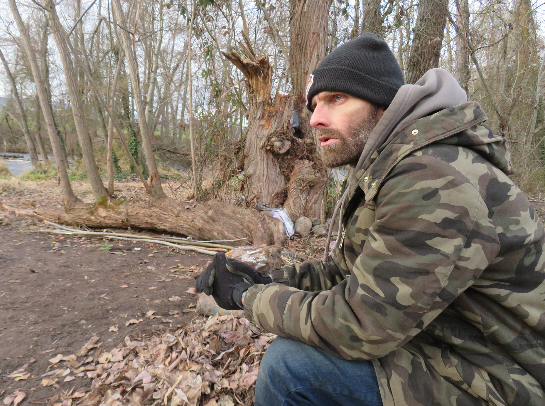 A photo of Travis “T-Bone” Greiner speaking and looking to the distance in a beanie and camo jacket.