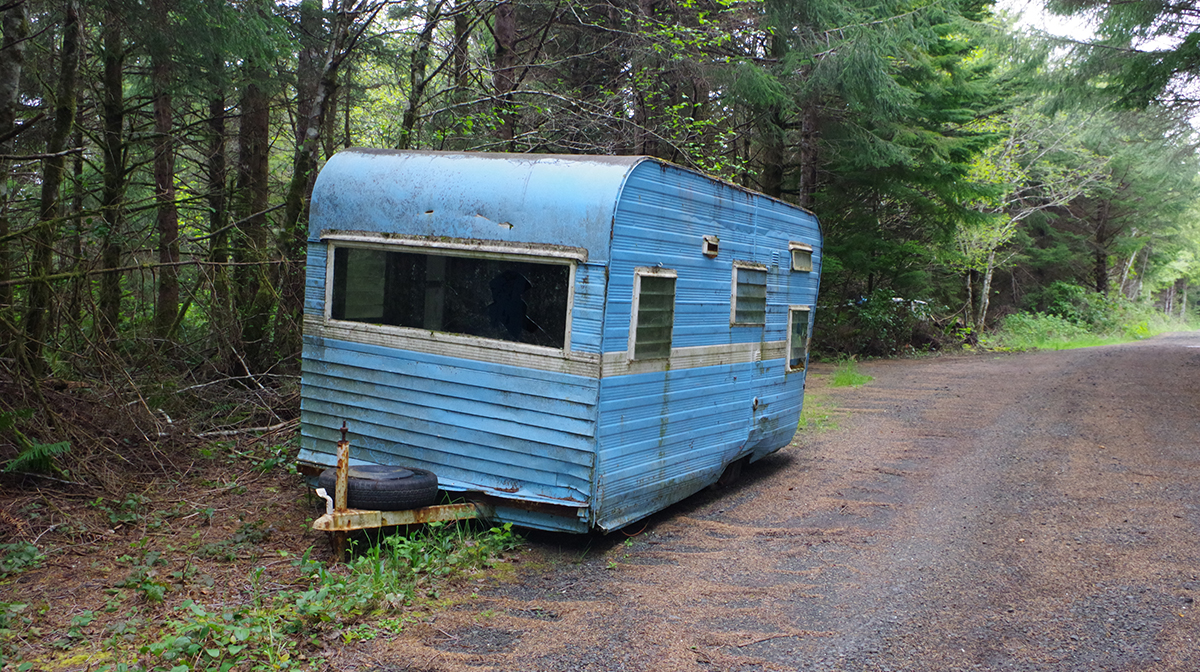 An abandoned blue RV in the forest