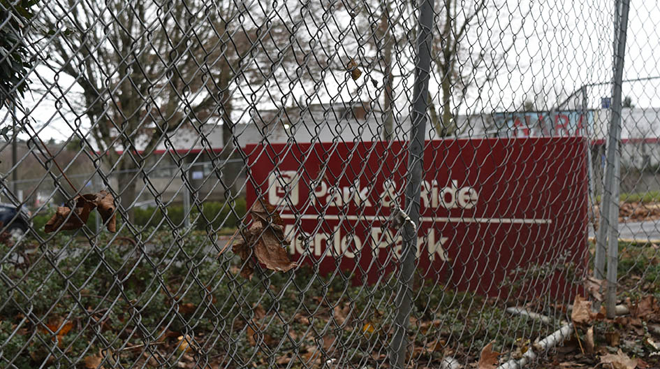 A photo of a fence in front of a sign that reads, "Park & Ride Menlo Park."