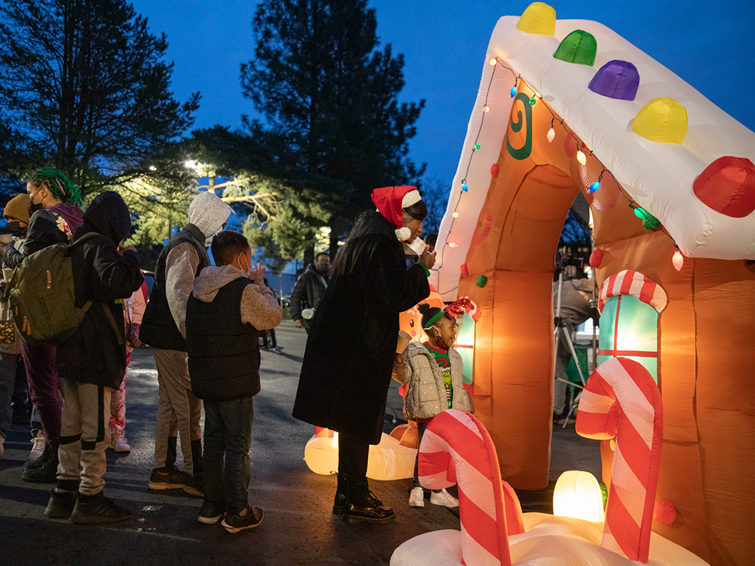 Photo of families and children standing in line beside an inflatable gingerbread house archway.