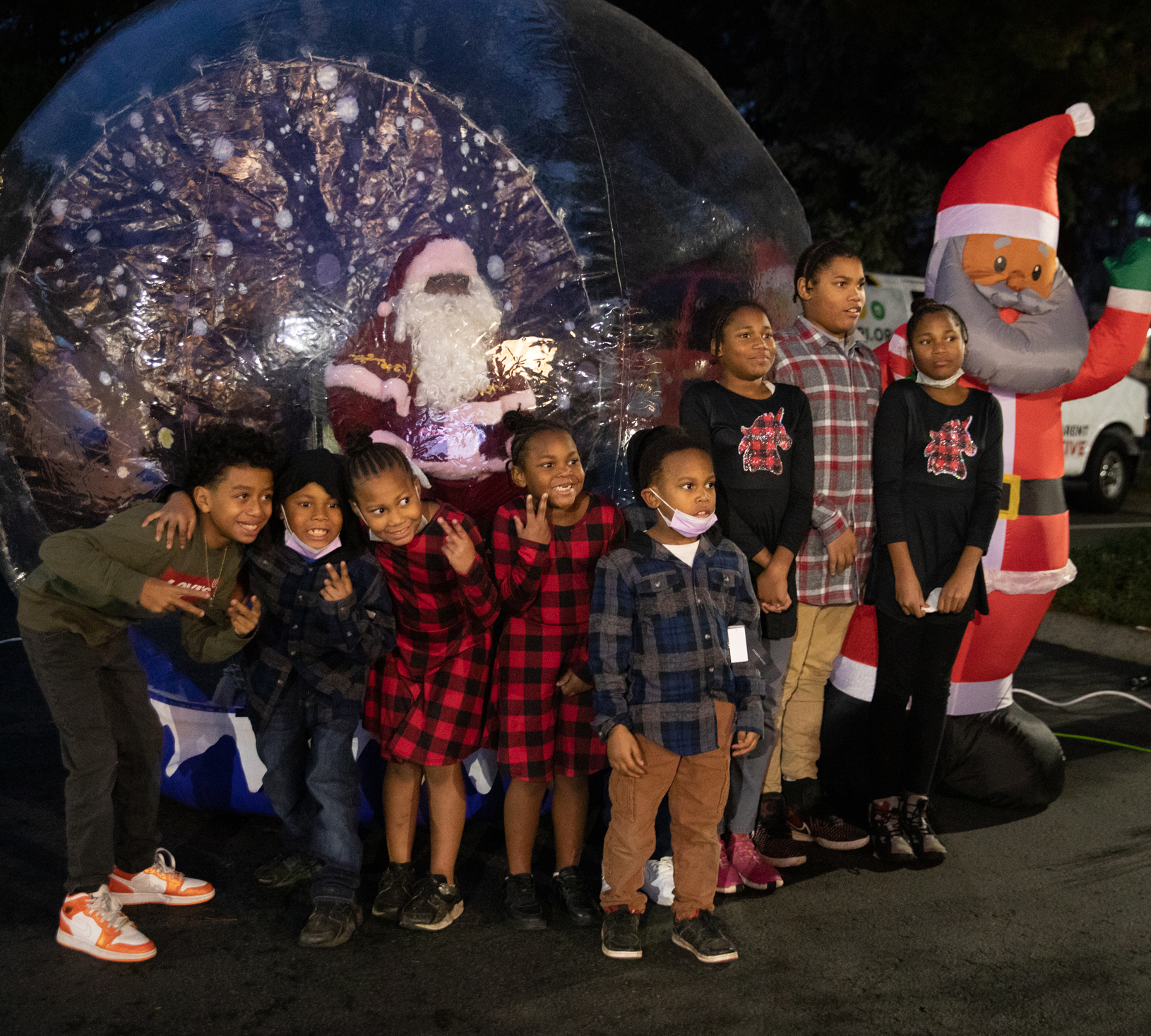 Photo of a group of children posing with Santa while he sits inside an inflatable snow globe.