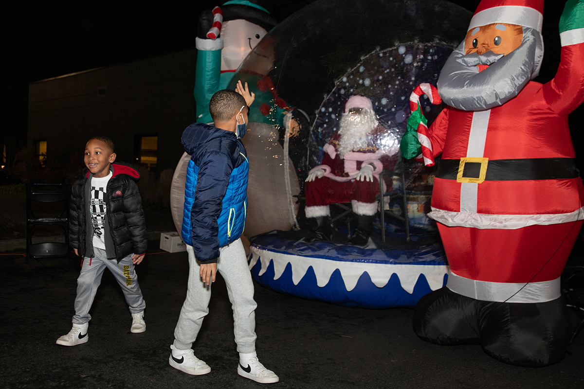 Two children, one waving goodbye to santa as they walk away.