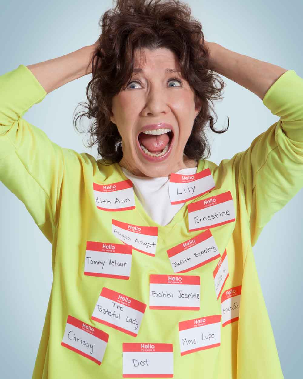 Lily Tomlin wearing name tags of characters she's portrayed