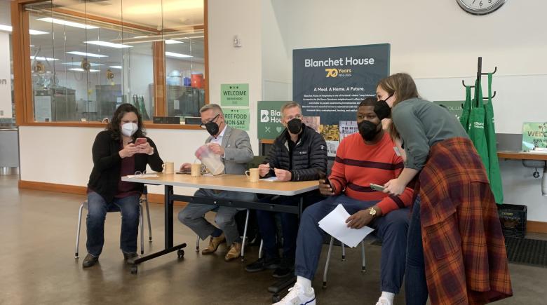 Photo showing Commissioner Dan Ryan and Mayor Ted Wheeler flanked by staff and volunteers during Nov. 1 town hall at Blanchet House