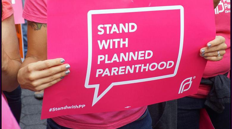 A woman holds a "Stand with Planned Parenthood" sign