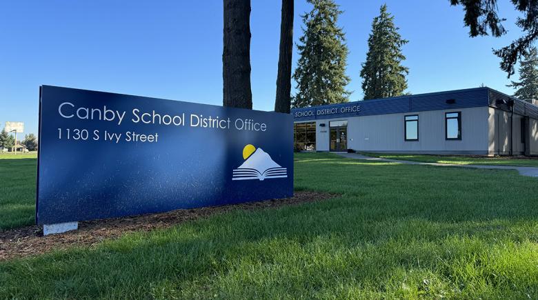 A photo of the Canby School District offices. A sign for the offices is in the foreground in a grassy area and the building is in the background behind it.