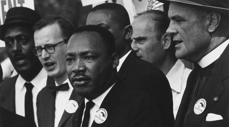 Martin Luther King Jr. looks toward a crowd as others stand around him