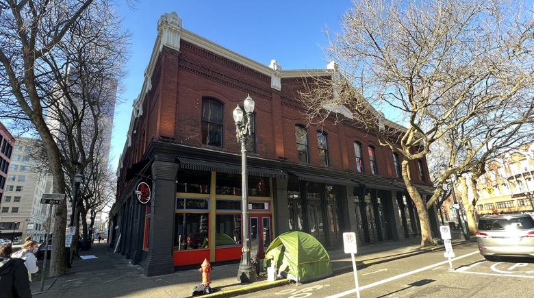 A building at the corner of SW Ash with a tent on a sidewalk.