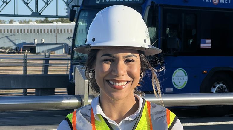 Mishele Martin smiles for a photo wearing a hard hat and her arms crossed across her chest.