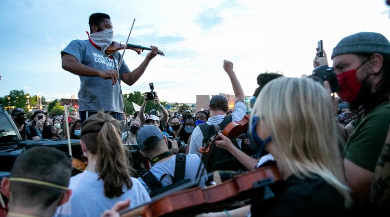 Jeff Hughes plays his violin, surrounded by a crowd