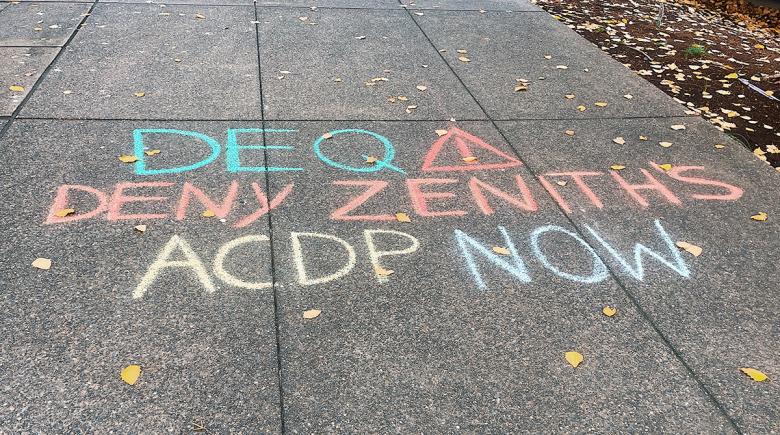Chalk on the sidewalk says "DEQ deny Zenith's ACDP permit now."