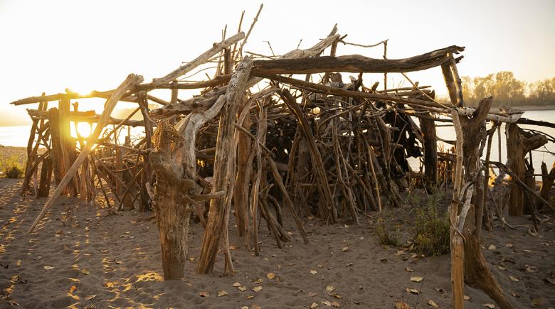 A driftwood structure built on sand.