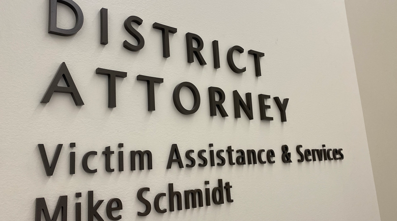 A tan wall with words on it that say, "District Attorney Victim Assistant and Service. Mike Schmidt."