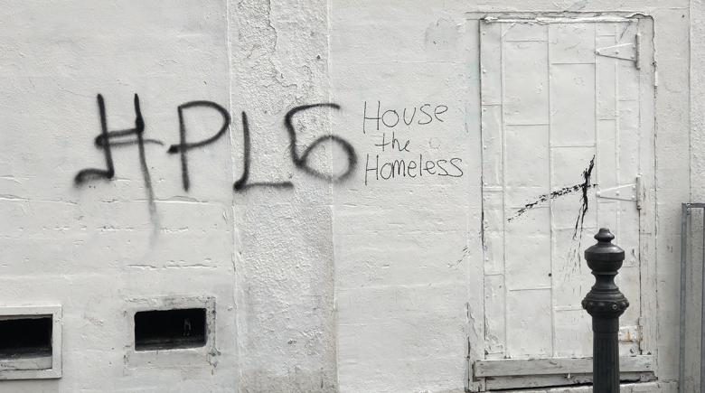 Graffiti on a building reads: House the Homeless