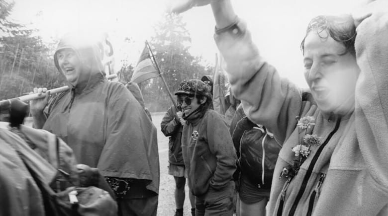 A group of people marching in the rain. The photo is black and white.