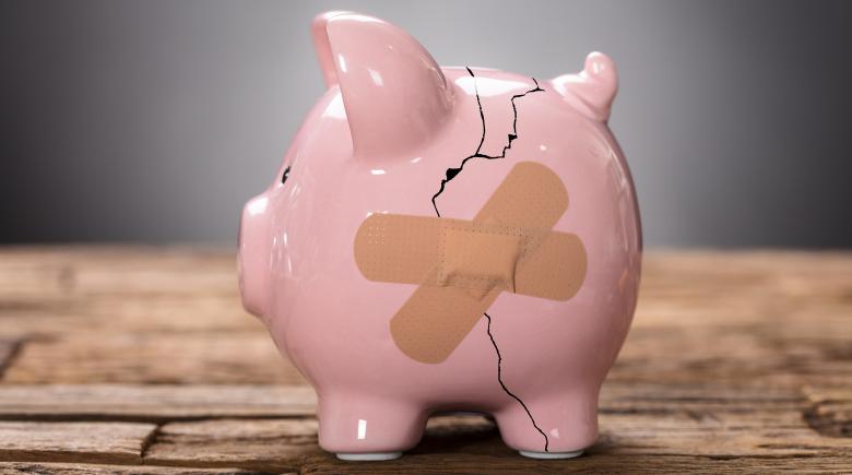 A cracked pink piggy bank is held together by two bandages.