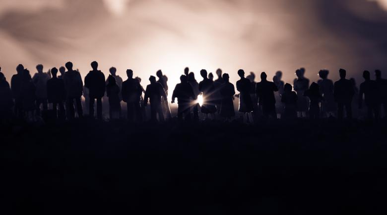 Silhouettes of a crowd standing in front of a foggy background