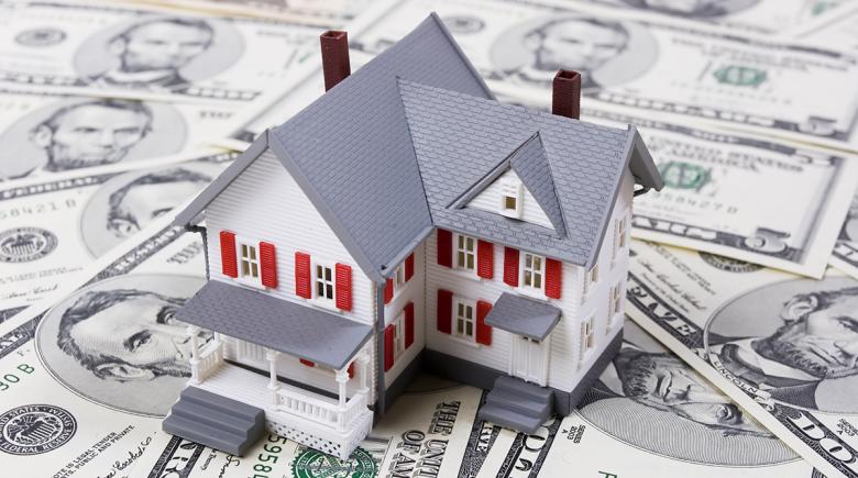 Photo illustration of a house on top of money