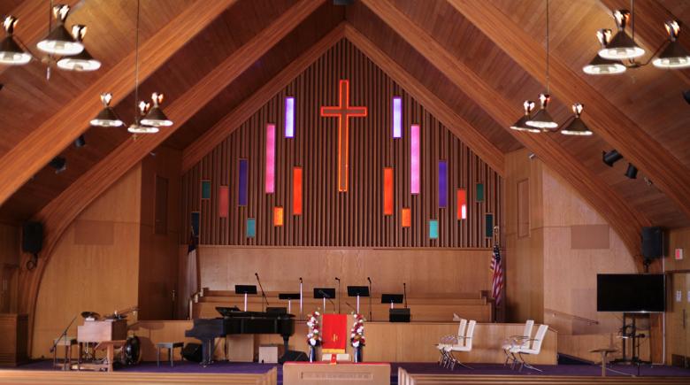 The inside of Morning Star Missionary Baptist Church shows wooden pews and a stained glass cross at the center of the pulpit.