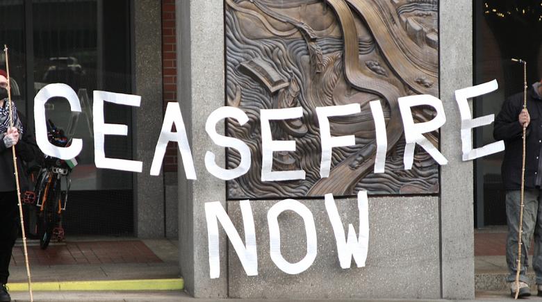 Organizers hold up a sign that says "ceasefire now" outside the Multnomah Building.