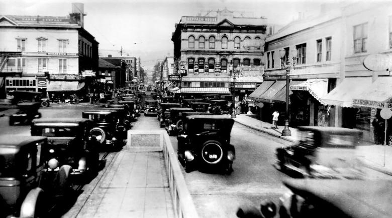A 1926 black and white photo of Burnside Avenue. The image shows old cars lined up on the street and buildings on either side of the road.