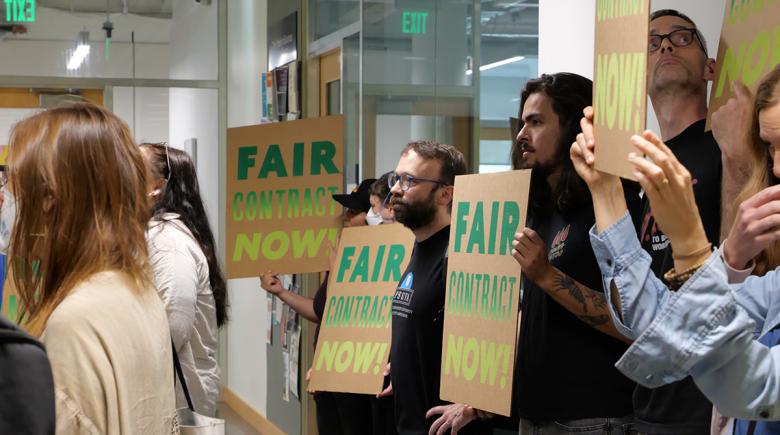 People hold signs that say "Fair contract now!"