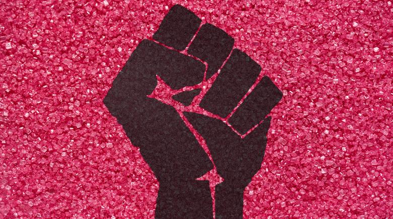Fist of resistance before a backdrop of pink glitter