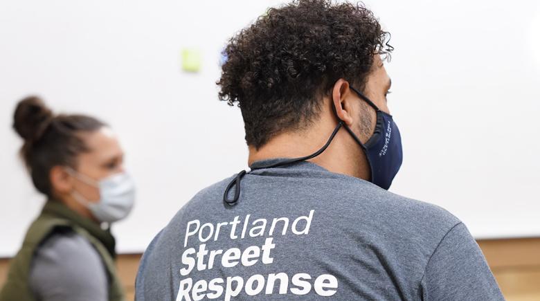 A photo of the back of someone's shirt and head. They are wearing a "Portland Street Response" t-shirt.