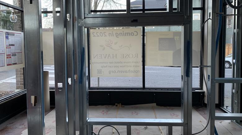 Inside the new Rose Haven shelter space. A poster hangs on the other side of the window reading "Coming in 2022 Rose Haven"