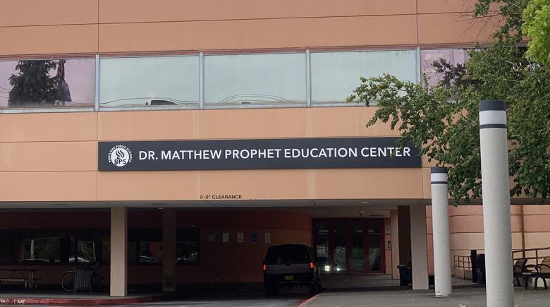 A building with a car driving toward the entry. Text on the building says, "Dr. Matthew Prophet Education Center"