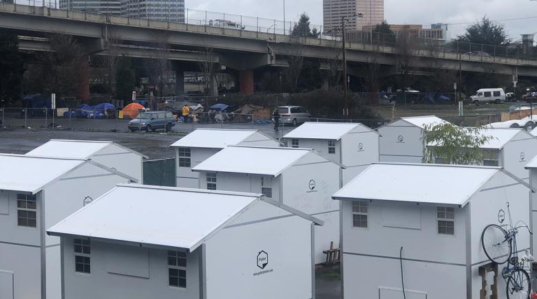 Tiny homes at the C3PO camp with the Portland skyline in the background