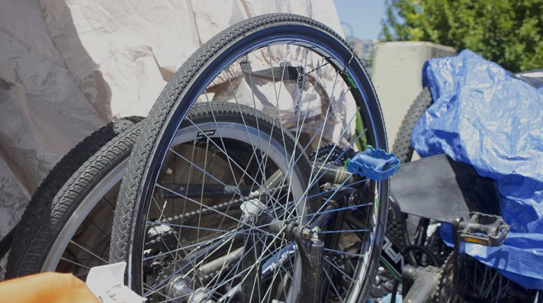 Several bike wheels next to each other in front of a tarp.