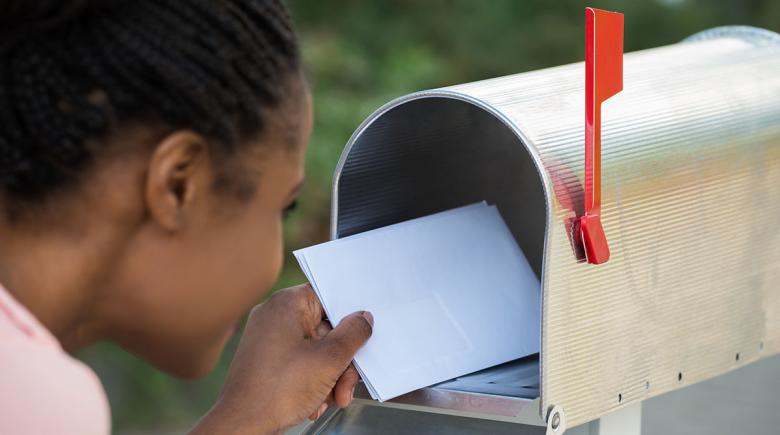 A student puts letters into a mailbox
