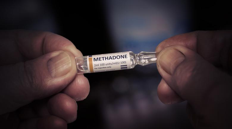 Hands holding a vial of methadone