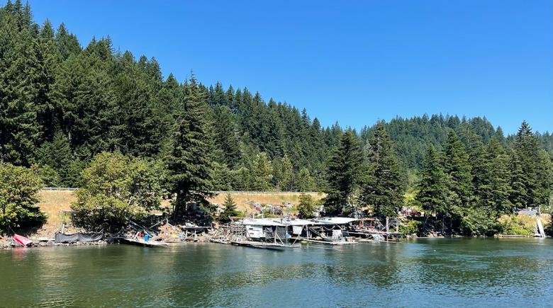 A view of a fishing platform along the Columbia River on a sunny day. The sky is blue and there are trees surrounding the river.