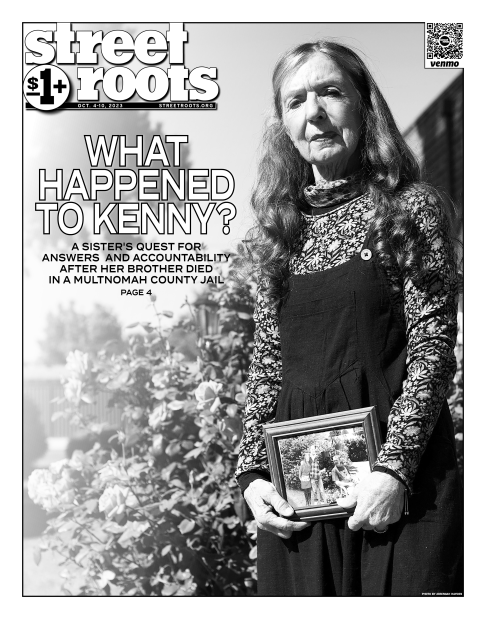 Cover of Street Roots Oct. 4, 2023 issue. In the background of the cover is a photo of Vickie Hanson among rose bushes and she is holding a framed family photo in her hands. Vickie has long brown hair that sits on her shoulders.